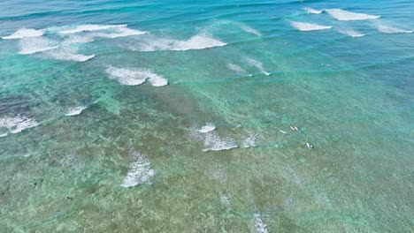 Birdseye-Shot-of-Surfers-on-Waves-on-Oahu,-Hawaii,-Bright-Blue-Turquoise-Water-with-White-Caps