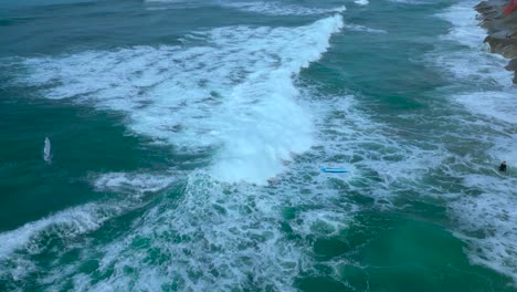 Drone-shot-of-surfers-playing-and-surfing-backwards-during-high-tide-in-Carlsbad-California