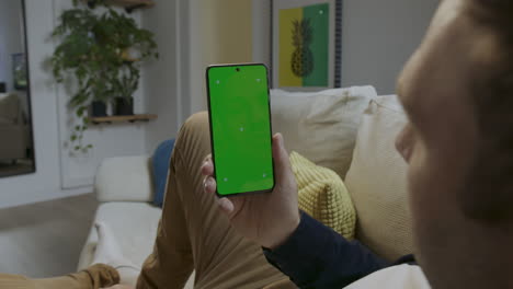 Digital-Interaction:-Person-Touches-Green-Screen-Smartphone-on-Sofa