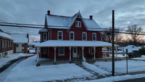 Luftaufnahme-Eines-Verschneiten-Einfamilienhauses,-Das-Mit-Weihnachtsbeleuchtung-Im-Winterschnee-Dekoriert-Ist