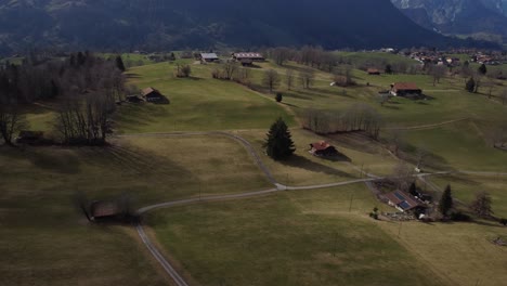 üppiges-Grünes-Gras,-Ackerland-Gebäude,-Luftaufnahme-Zeigen-Schneebedeckten-Berg