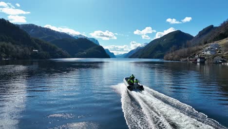 Aerial-overtaking-RIB-boat-with-tourists-on-fjord-safari-at-beautiful-spring-day