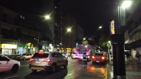Night-bus-drive-in-rivadavia-avenue-city-lights-with-rainy-weather-latin-america-public-transport-in-buenos-aires-city-argentina-neighborhood-transit-at-night,-asphalt