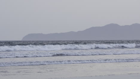 Static-shot-of-waves-rolling-onto-the-bay-at-canas-island-with-hills-behind