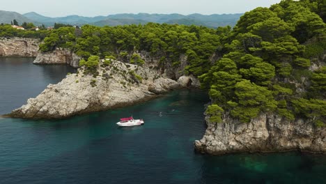 Kalamota-Island,-Adriatic-Sea,-Croatia---A-Sailboat-Gently-Sailing-Near-the-Steep-and-Rugged-Cliffs---Aerial-Drone-Shot