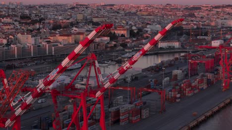 Aerial-Telephoto-closeup-of-red-and-white-ship-to-shore-port-container-cranes-and-city-backdrop