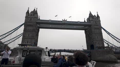 As-travelers-cruise-along-the-river,-they-pass-beneath-London's-Tower-Bridge,-embodying-the-essence-of-travel,-exploration,-and-architectural-admiration