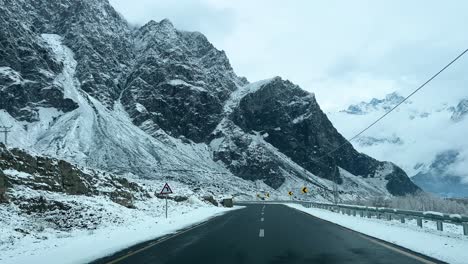 Coche-Conduciendo-Por-Una-Carretera-En-Skardu-En-Un-Paisaje-Cubierto-De-Nieve-Y-Altas-Montañas