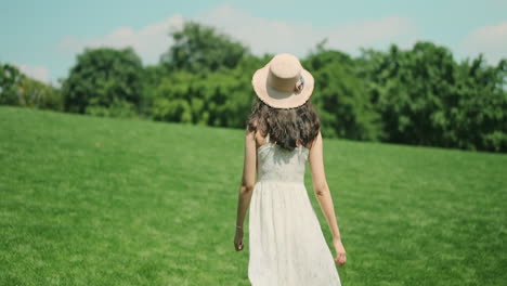 Cámara-De-Seguimiento-De-Una-Hermosa-Joven-Modelo-Con-Un-Lindo-Vestido-Blanco-Corriendo-En-El-Parque-Verde,-Cámara-Lenta