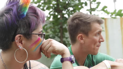 Eine-Frau-Mit-Pride-Farben-Auf-Ihrem-Gesicht-Unterhält-Sich-Mit-Ihren-Freunden-Während-Des-Midmo-Pridefests-In-Columbia,-MO
