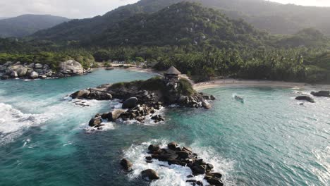 Drone-flying-backward-from-wilderness-coastal-landscape-from-Tayrona-National-Park,-Colombia