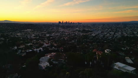 Los-Angeles-city-skyline-and-suburbs-during-sunset,-aerial-drone-view