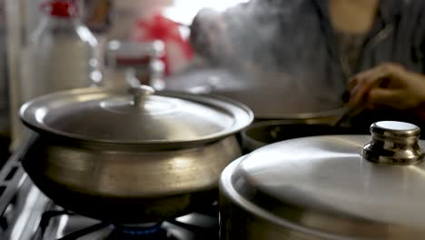 Cooking-pots-on-a-stove,-individuals-lifting-lids-and-blending-ingredients-amid-swirling-vapor,-embodying-the-essence-of-culinary-artistry-and-gastronomy