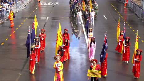 Vietnamesische-Frauen-In-Traditioneller-Kleidung,-Gefolgt-Von-Vietnam-Veteranen-Und-Ihren-Familien,-Gehen-Die-Straße-Entlang-Und-Nehmen-An-Der-Anzac-Day-Parade-Teil,-Um-Diejenigen-Zu-Ehren,-Die-Gedient-Und-Opfer-Gebracht-Haben