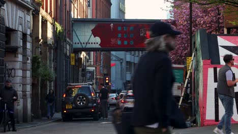 Vibrant-street-scene-in-Manchester's-Northern-Quarter,-red-artwork-bridge,-pedestrian