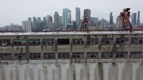 Flight-into-abandoned-building,-Montreal-skyline-in-the-background