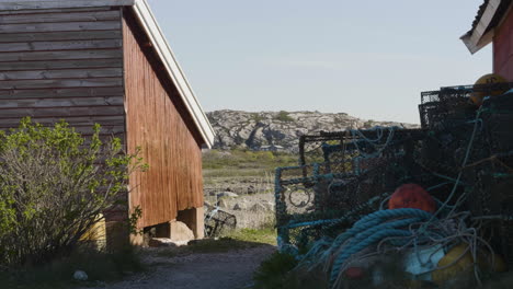 Fishing-Gear,-Lobster-Pots-Outside-Red-Fisherman's-Hut,-Rocky-Landscape-background
