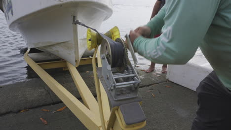 Close-up-shot-of-a-man-reeling-a-boat-onto-a-small-trailer-ready-to-go-home