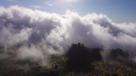 Vista-Aérea-De-Drones-De-Nubes-Blancas-Moviéndose-Sobre-Las-Laderas-De-Las-Montañas-Del-Volcán-Haleakala