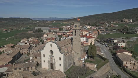 Luftaufnahme-Einer-Typischen-Kirche-In-Einem-Dorf-In-Katalonien,-Deren-Kirchturm-Mit-Einer-Unabhängigkeitsflagge-Gekrönt-Ist