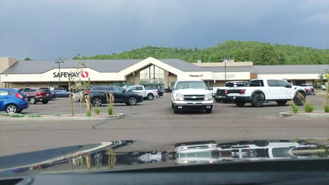 White-Chevrolet-truck-leaving-parking-lot-of-shopping-mall,-POV-from-inside-car