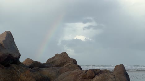Über-Den-Stürmischen-Meereswellen,-Die-Gegen-Die-Zerklüftete-Und-Felsige-Küste-Von-Zahara-Krachen,-Schmückt-Ein-Regenbogen-Den-Himmel-Und-Verkörpert-Den-Reiz-Und-Die-Naturwunder-Der-Küstenlandschaft