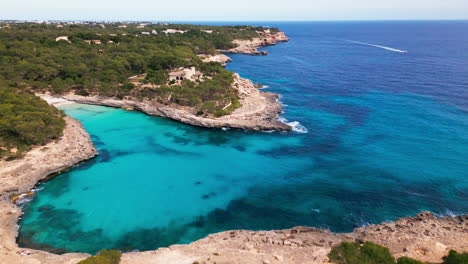 Aerial-view-of-Cala-Mondrago's-turquoise-waters-and-lush-woodland-in-Mallorca
