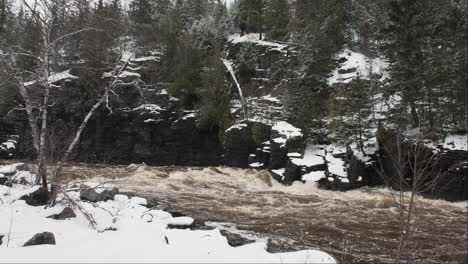 Der-Fluss-Fließt-In-Einem-Winterlichen-Schneesturm-Entlang-Einer-Felsigen-Felswand