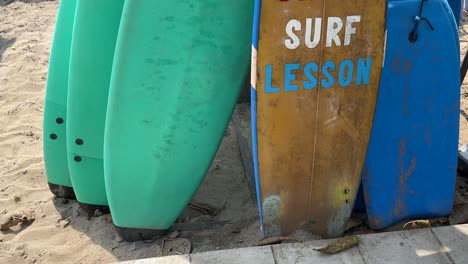 Surfunterricht-Gemalt-Auf-Einem-Surfbrett-Inmitten-Einer-Gruppe-Von-Surfbrettern,-Die-Im-Sand-Des-Legian-Beach,-Bali,-Indonesien-Ruhen