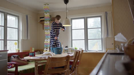 Boy-dejected-after-tall-stacked-wooden-block-tower-on-kitchen-table-collapses