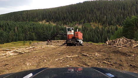 Logging-machine-and-majestic-national-forest-hill-in-front,-driving-POV-shot
