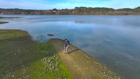 Fotógrafo-Masculino-Con-Cámara-Y-Trípode-Tomando-Fotos-En-La-Orilla-Del-Lago.