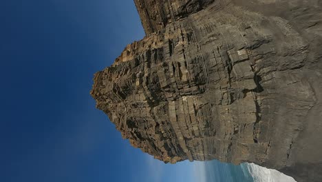 Vertical-FPV:-Flight-up-rugged-rock-strata-sea-stack,-Portugal-coast