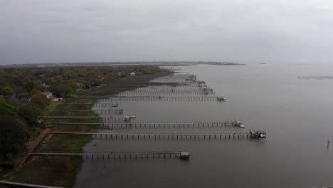Wide-aerial-shot-flying-over-long-fishing-docks-along-Charleston-Harbor-on-a-hazy-day-in-Old-Village-Mount-Pleasant,-South-Carolina