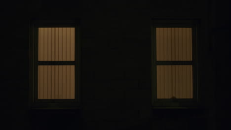 Two-windows-with-reflection-of-car-passing,-at-night-in-city