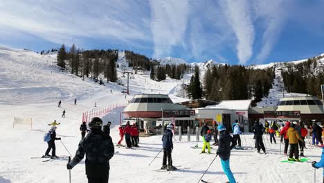 Downhill-skiers-queuing-for-the-ski-lift-terminals-to-get-on-at-Nassfeld-Alpine-ski-resort,-Austria