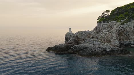 Kalamota-Island,-Adriatic-Sea,-Croatia---The-Sight-of-a-Lighthouse-Positioned-on-a-Rugged-Cliff---Aerial-Pullback-Shot