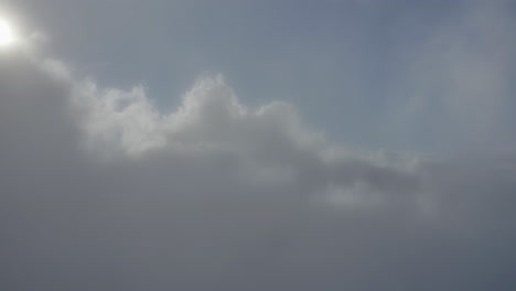 Vista-Aérea-Del-Dolly-A-Través-De-Nubes-Blancas-A-La-Luz-Del-Día-Debajo-De-Un-Cielo-Azul.