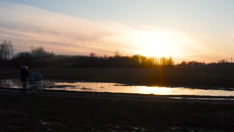 Sonnenuntergang-Reflexion-Auf-überfluteten-Feld,-Alleinerziehende-Mutter-Mit-Kinderwagen-Genießen-Sie-Die-Zeit