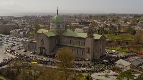 Panoramic-aerial-static-establishing-view-of-Galway-Cathedral-crowd-gathered-to-watch-parade-on-a-sunny-day