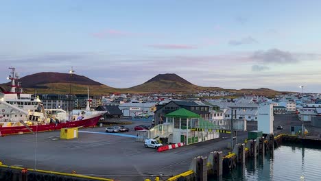 Early-morning-view-of-Vestmannaeyjar-harbor-with-ships-and-colorful-buildings,-calm-weather