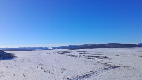 4K-footage-of-a-snow-field-with-endless-hills-behind-it-from-a-drone