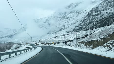 Car-driving-on-a-road-in-Skardu-in-landscape-covered-with-snow-and-high-mountains---It-is-cloudy