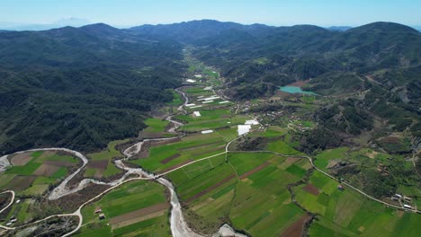 Un-Río-Sereno-Que-Serpentea-A-Través-De-Un-Paisaje-Impresionante:-Valle-Con-Parcelas-Verdes,-Campos-Primaverales-Y-Un-Encantador-Paisaje-De-Aldea-En-Albania
