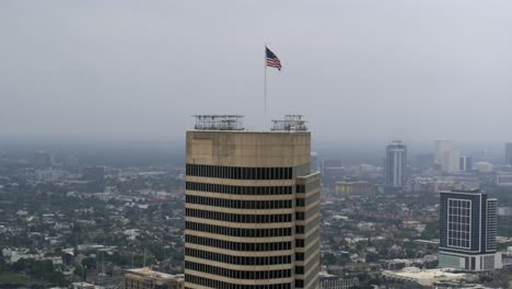 Vista-Por-Drones-De-La-Bandera-Estadounidense-Ondeando-En-La-Cima-Del-Rascacielos-De-Houston