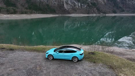 Tesla-Model-3-In-Wunderschönem-Babyblau-Parkt-Am-Rande-Des-Sees