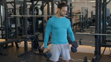 Muscular-European-Man-Lifting-Weights,-Doing-Alternating-Bicep-Curls-At-Gym