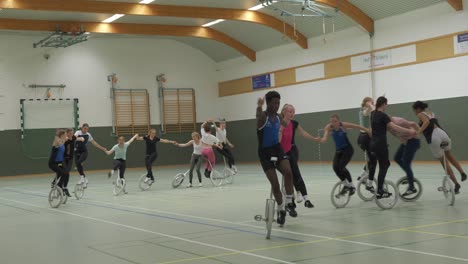 Group-of-young-women-unicyclists-balancing-on-unicycles-together-at-practice-session