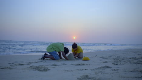 Boys-building-a-sandcastle-at-the-beach-in-sunset