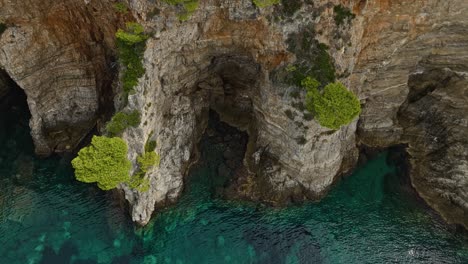 Kalamota-Island,-Adriatic-Sea,-Croatia---The-Clear-Blue-Waters-Below-the-Steep-and-Rugged-Cliffs---Orbit-Drone-Shot